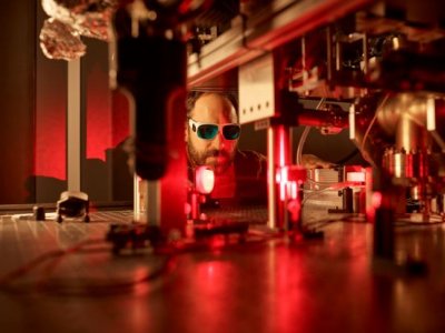 Male researcher under red light in a quantum physics lab.